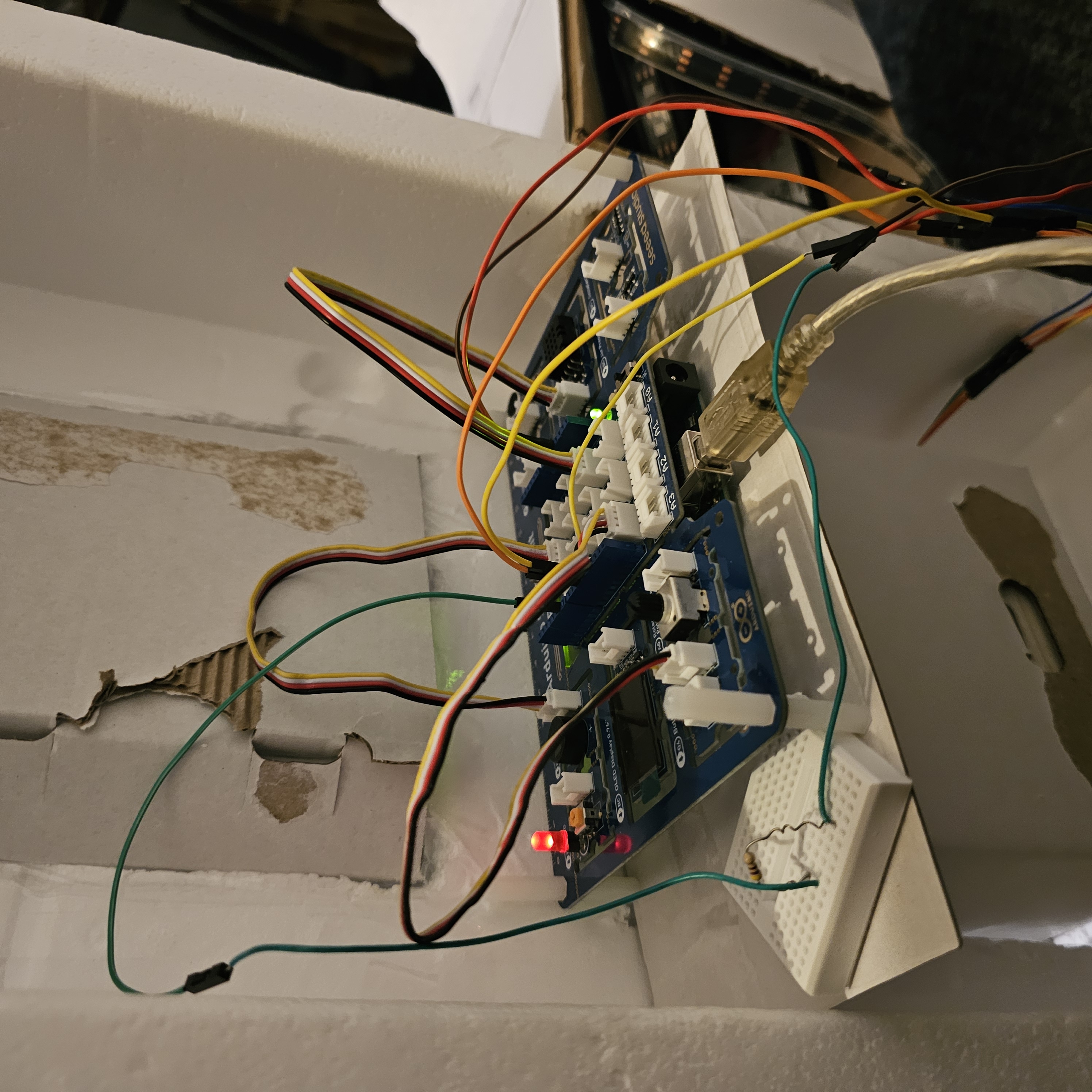 Back of unfinished prototype of dash console. The potentiometer on the board controls the brightness of the led strip. A dial would be routed to the front of the console as dial hardware was the ideal interaction for visual brightness and hand tuning coordination. Ideally a 3d-printed box or a smaller board could be used for this system. Each individual sensor coudl also be attached to the conseol structure rather than being hoste don one singular board. This would reduce the size footprint, allowing for practical fitting. This setup could be retrofitted into an actual car dash console for application. It also does not cost the same amount that dealerships or manufacturer charge for technology packages; and that is if the service is offered.